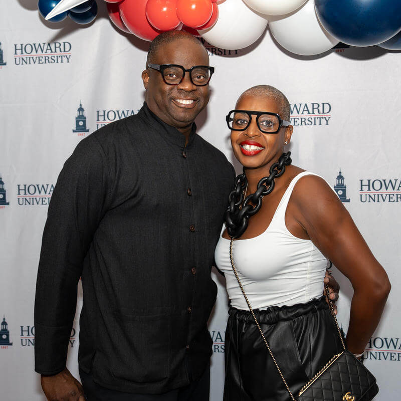 Howard alum posing for a photo in front of a Howard University backdrop