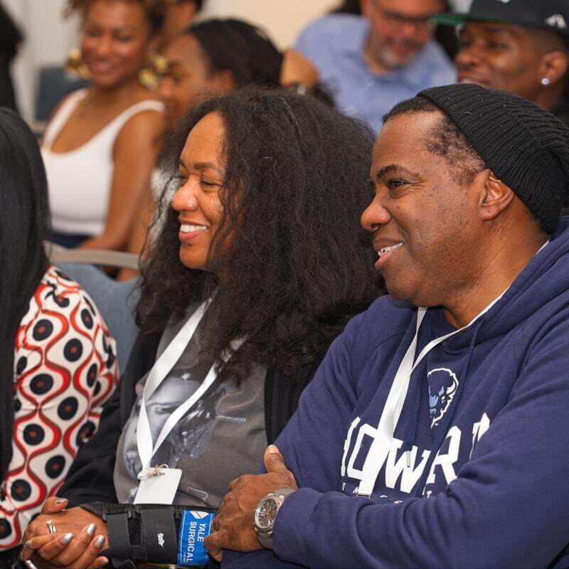 Guests looking and smiling at the speakers talking up front