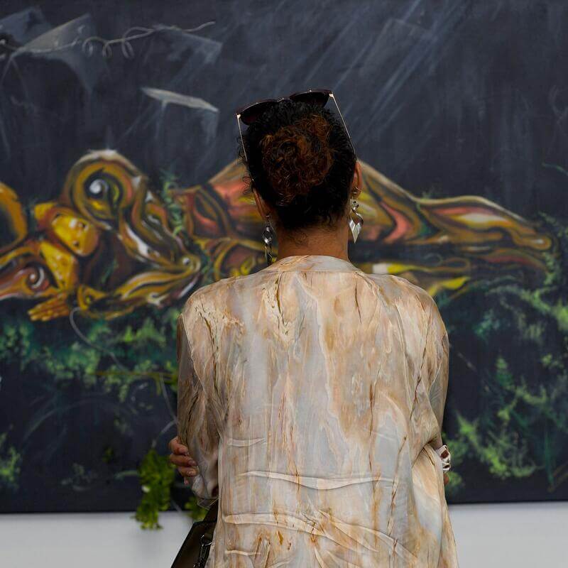Guest looking at a painting with her back turned toward the camera.