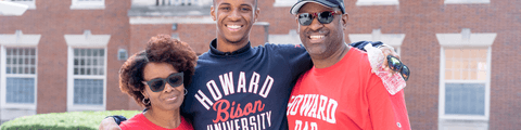 A Howard student with his parents, who are wearing Howard merchandise.