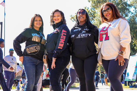 Four alumni pose for a photo at Homecoming