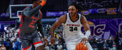 Howard men's basketball player driving by defender.