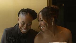 Rachel Burks-Crouch (B.S., 2005) and Kimberly Burks-Crouch (B.A., 2003) holding hands and smiling at their wedding