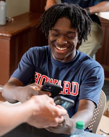 Howard student smiling and scanning a code on another student's phone
