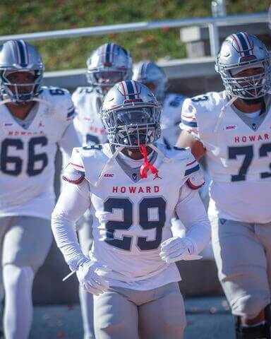 Bison football players number 66, 29, and 73 running onto the field.