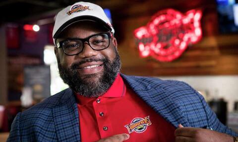 Nicholas Perkins pointing to logo on Fuddruckers shirt
